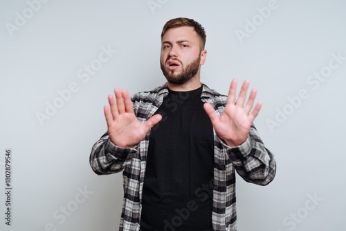 Fotografia portrait of young man adopts a defensive posture by raising his hands on white b