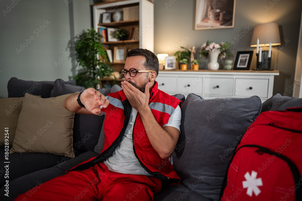 Obraz premium Paramedic man yawning after long shift at home