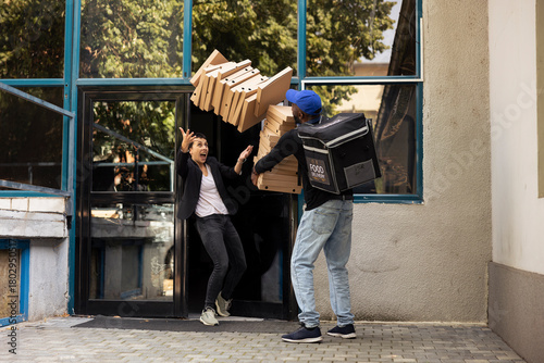 Bilde på lerret African american courier with backpack struggles with tall pizza pile, dropping a massive stack of boxes at the doorstep