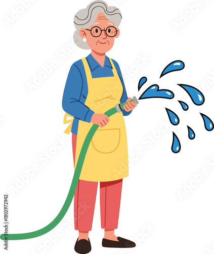 Smiling elderly woman with grey hair and glasses in a yellow apron watering with a green garden hose.