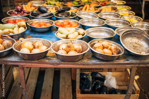 Various fresh vegetables, including onions and tomatoes, displayed on a market stall