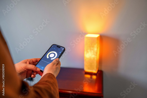 Woman controlling smart lighting at home using smartphone. Concept: smart home, control lighting from smartphone.