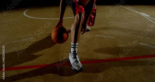 Canvas Print Dribbling player lower body handling ball on gym court with painted lines, weari