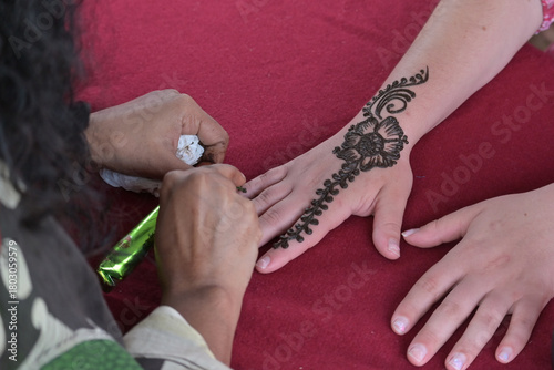 Henna artist applies temporary body art using a paste made from the henna plant on female hand