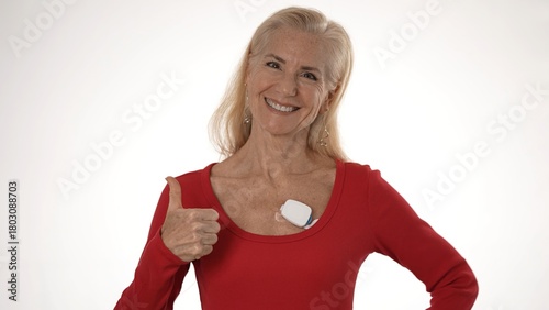 Mature woman shows a positive attitude while wearing a heart monitor for atrial fibrillation, highlighting her commitment to health