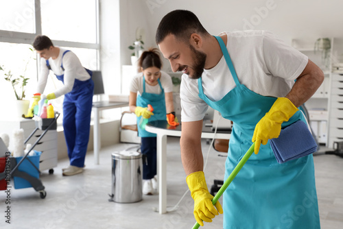 Male janitor mopping agains...