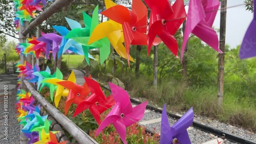 colorful pinwheels hanging on the garden fence