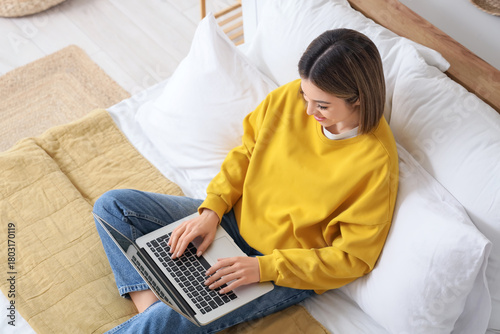 Young woman using laptop to...