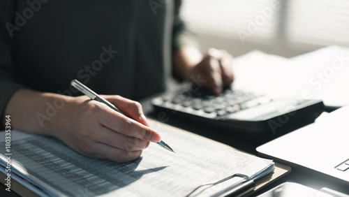 Fotografie Hands writing financial records and using a calculator, representing accounting tasks, budgeting plans, tax calculation, cost management, and financial reporting in a professional office setting