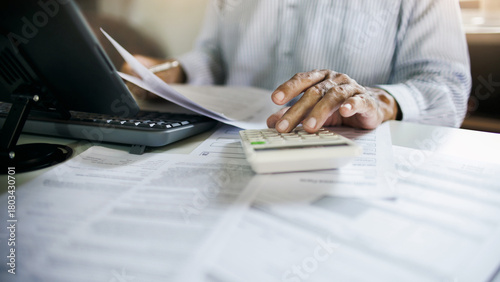 close up shot, accountant working in office with documents using calculator to calculate monthly expenses, budget, tax to summarize monthly performance results