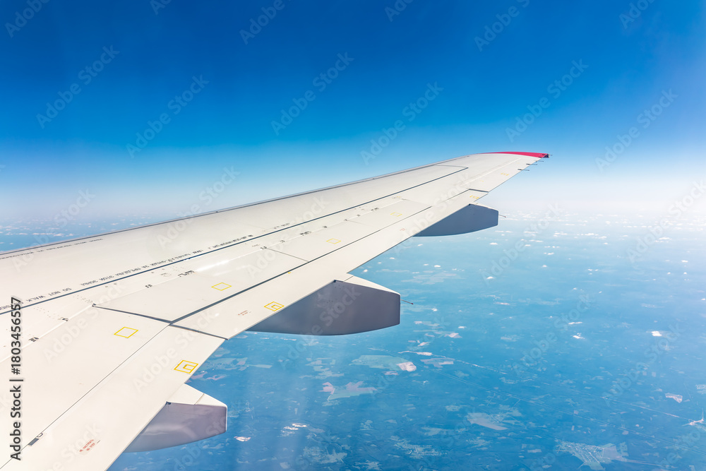 Fototapeta premium View from the airplane window at a beautiful blue clear sky and the airplane wing