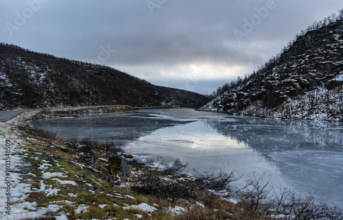 Swamp with small pine trees covered in early winter morning frost reflecting in pond. national park at sunrise with fog rising, scandinavia