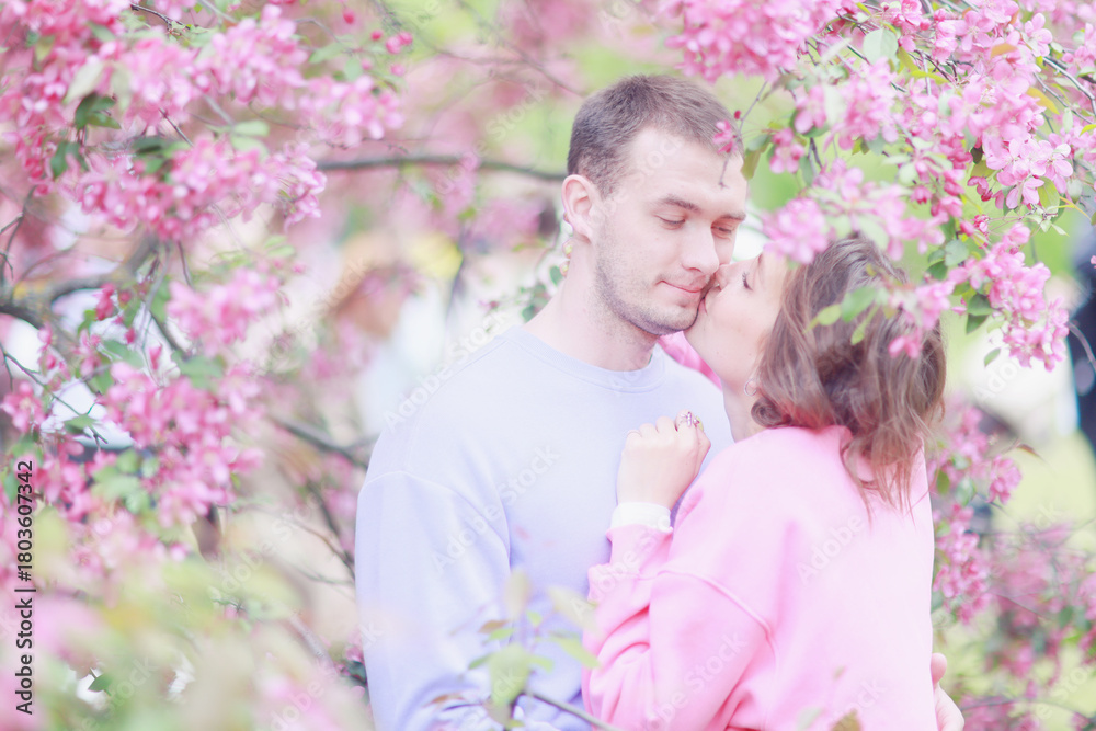 Obraz premium A couple in love among a pink cherry blossom in spring, a man and a woman hug