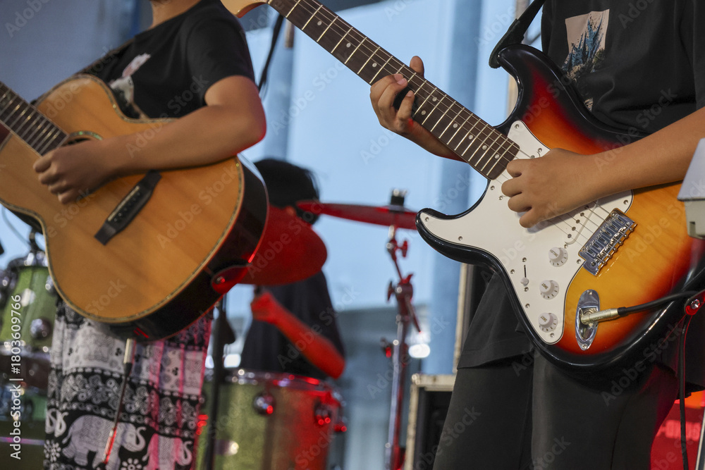 Fototapeta premium Passionate musician playing electric guitar in live band performance. music concert on stage with guitarist creating an energetic rock sound with an acoustic player