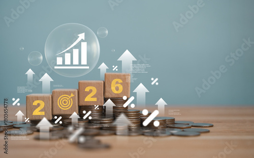 A wooden block with the year 2026 on top of a stack of coins represents investment strategies, financial planning, income goals, growth, action and success for the new year.