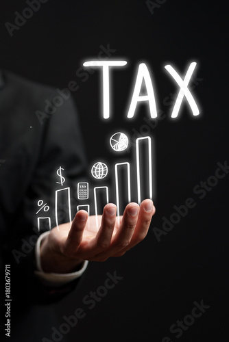 Businessman illustrating tax growth through a glowing graph in a dark setting © fotofabrika