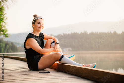 Woman running by the lake on a sunny day. Active lifestyle and outdoor fitness concept.