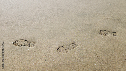 Footprints in the dune sand tell a quiet story of a solitary stroll along the shoreline