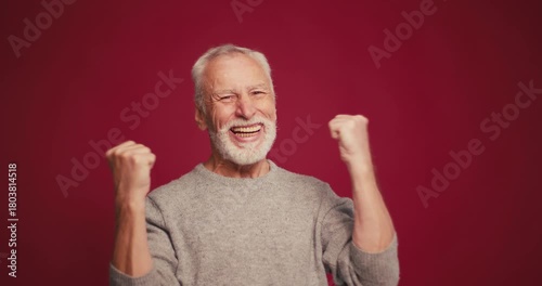 Handsome, smiling gray haired senior man win money, having good news isolated on red background