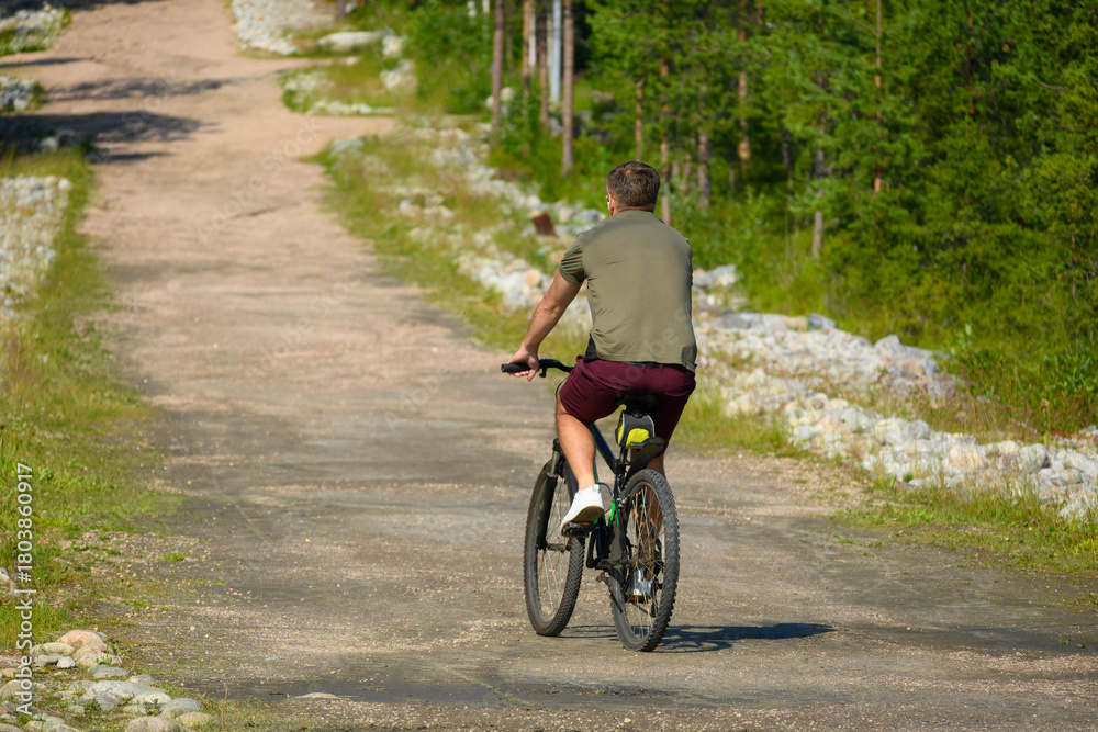 Obraz premium Man with Bicycle on Road Near Green Park in Summer