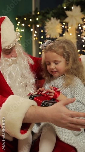 Santa Claus giving Christmas gift to smiling little girl