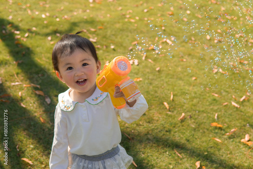 A child plays with a bubble blower, creating bubbles in an autumn park.