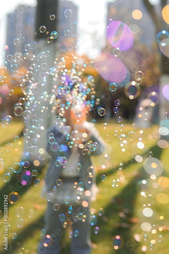 A child plays with a bubble blower, creating bubbles in an autumn park.
