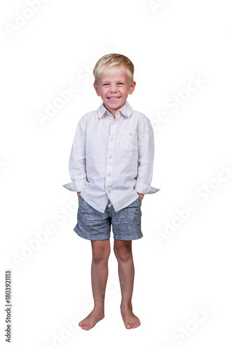 A 5-year-old boy laughs infectiously. The child, wearing a light shirt and gray shorts, stands barefoot at full height with his hands in his pockets. Isolated on a white background. Vertical.