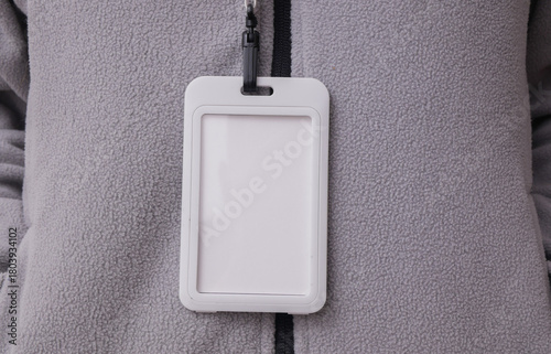 Blank white id badge hanging on the neck of a woman in a sports fleece sweatshirt. Trainer, gym instructor, sports and fitness concept. Design mockup.