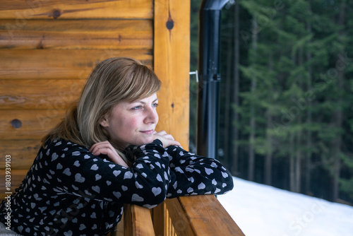 Woman relaxing on winter cabin balcony thinking