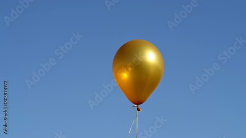 Golden Balloon Floating in a Clear Blue Sky - A Symbol of Celebration.