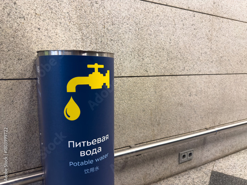 Drinking fountain at the airport with sign in three languages demonstrating care for different cultures and nationalities. Multilingual sign pointing to drinking fountain