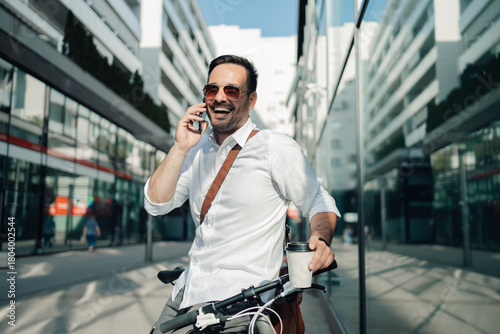 Stylish businessman commuting by bicycle making phone call
