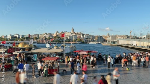Wallpaper Mural Time lapse of Crowds at Eminonu square near iconic Balik Ekmek fish sandwich boats with Galata Tower and waterfront on a sunny day Torontodigital.ca