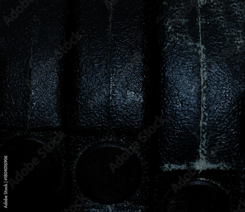 Close-up of a black dumbbell with a rough surface and an abstract pattern