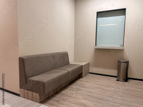 A clean office mailing room featuring a simple brown upholstered bench with a wooden base.
