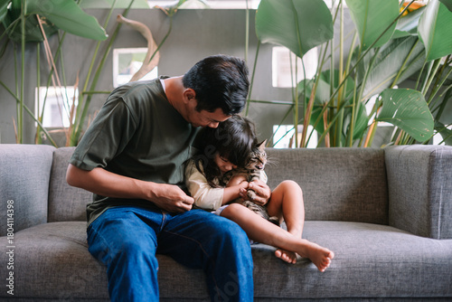 Loving Father and Daughter Cuddling Pet Cat Together on Sofa