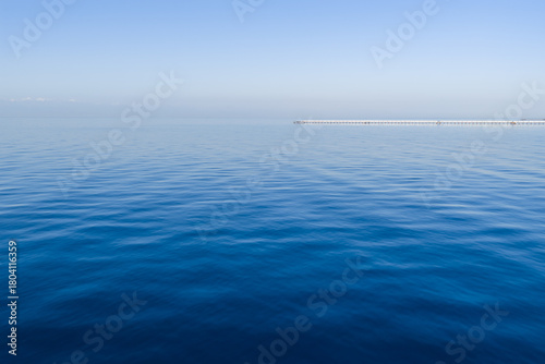 Fototapeta Naklejka Na Ścianę i Meble -  Calm blue sea with gentle waves under a clear sky. Minimalistic seascape with soft horizon and tranquil water texture