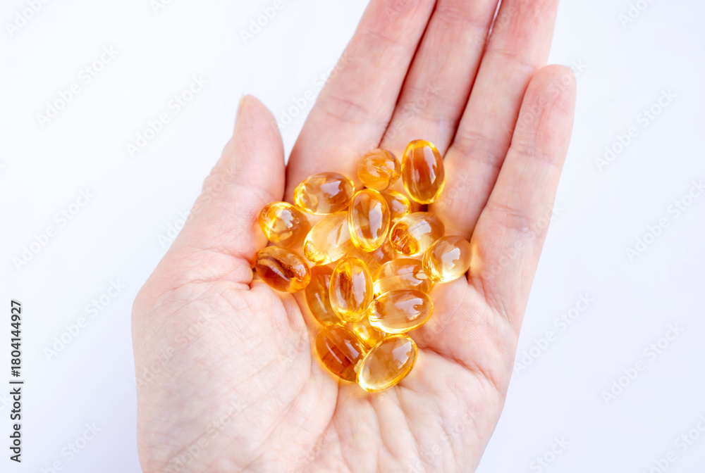 Fototapeta premium Omega 3 capsules, vitamin D, vitamin E, fish oil capsules in hand on a white background. Biologically active food supplement. Proper healthy eating.