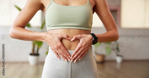 Fitness, heart hands and woman in gym with belly, gut health and inspiration for body goals. Sport, stomach and athlete in studio with emoji, weight loss and digestion support in wellness routine.