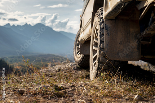 Close up photo of car wheel. 4x4 offroad ready car is standing at view point against mountain valley