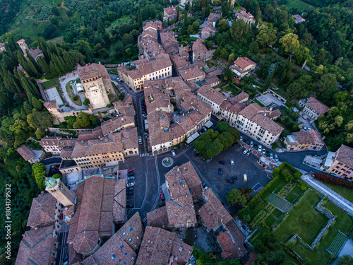 Aerial view of terracotta rooftops nestled in verdant hillsides, ancient structures casting shadows in the fading light, Piazza Garibaldi a focal point, Asolo, Veneto, Italy.
