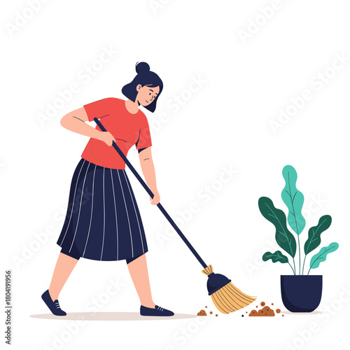 A woman is diligently sweeping up dirt and debris from the floor near a potted plant.