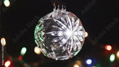 A close-up shot of a clear, faceted Christmas ornament reflecting colorful lights, creating a festive and sparkling display.