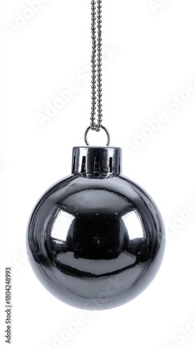 A single dark gray, reflective Christmas ornament hangs by a silver chain against a stark white backdrop, symbolizing holiday decoration.