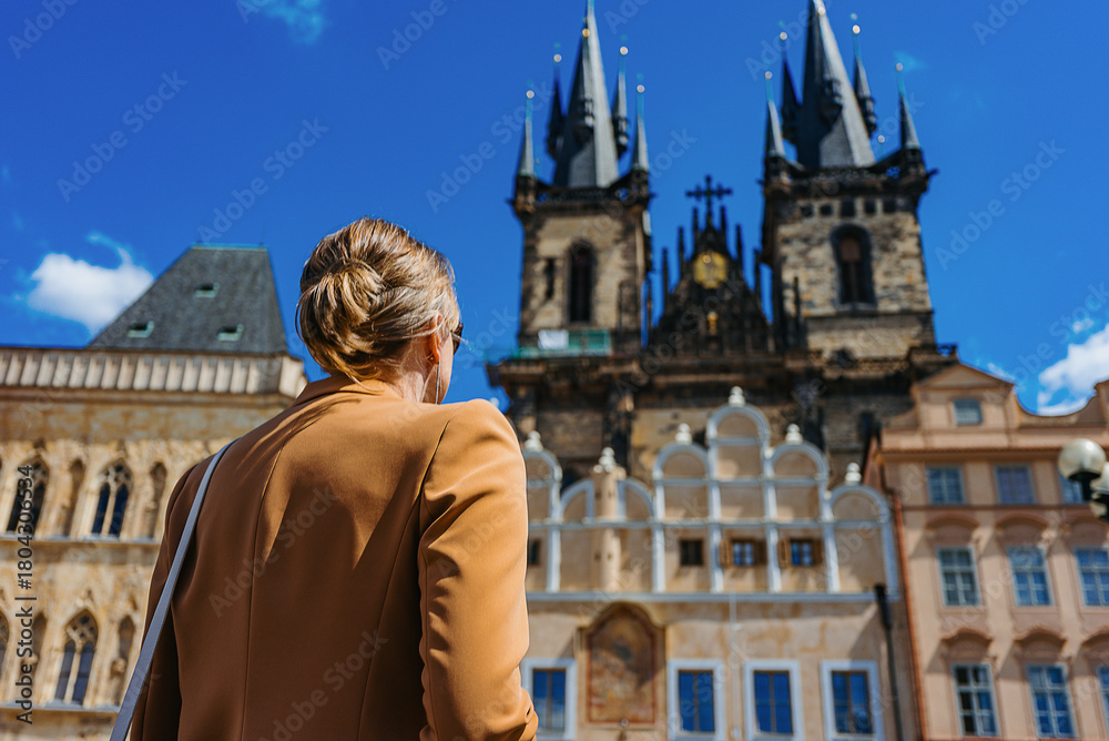 © M-Production - Female tourist explores historic Prague Old Town Square.