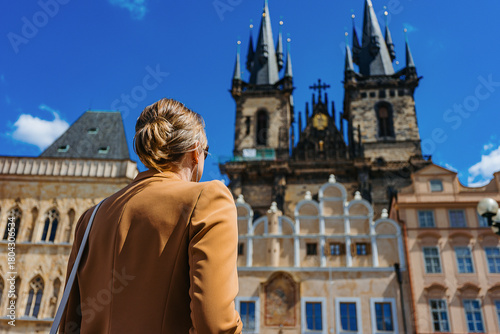 Female tourist explores historic Prague Old Town Square.