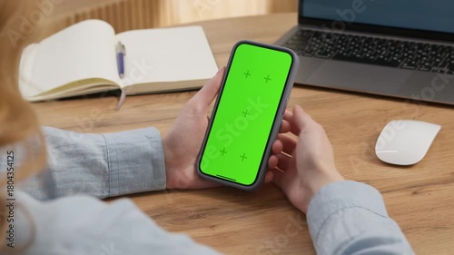 Woman sit use digital tech cell phone open green screen mock up. Hand scroll phone web site swipe unlock. Girl hold mobile closeup. Turn on chroma key page Cozy home background. Online app copy space