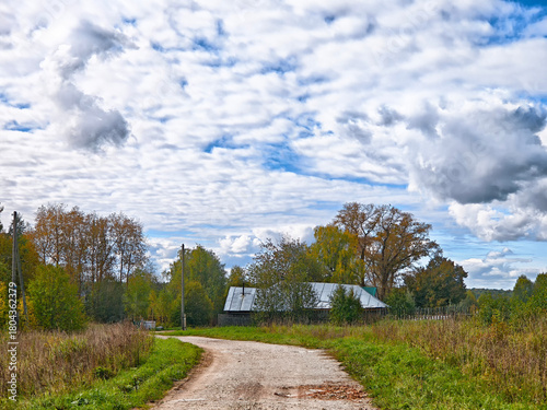Scenic dirt road winding through rural landscape under a cloudy sky in autumn