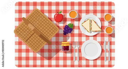 a top view flat lay of summer picnic spread with sandwiches fruit juice and a basket on a red checkered blanket.